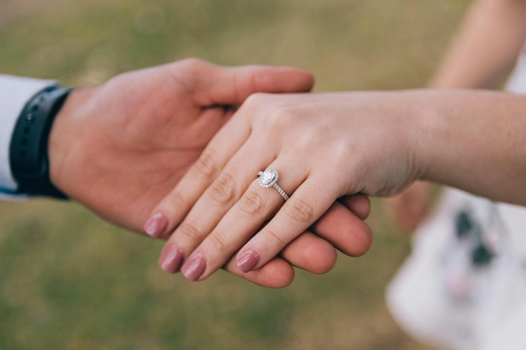 Romantic gesture of couple holding hands, showcasing a diamond engagement ring.