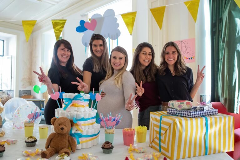 Pregnant woman celebrates a baby shower with friends, gifts, and decorations indoors in Portugal.